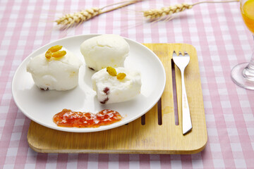 Close-up, rice steamed sponge cakes in white plate on wooden tray on checkered tablecloth, jam, tableware, ripe wheat ears and orange juice; dessert, nutritious breakfast