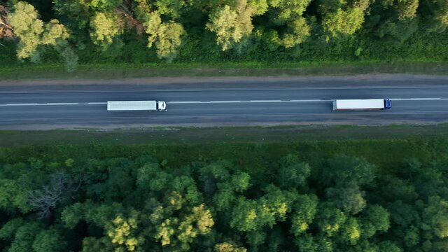 View of the highway on which freight trucks with trailers are moving. Transport industry, provision of delivery services, delivery of goods to the warehouse. High quality. 4k footage.