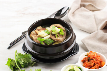 Gori Gomtang (Sokkori Gomtang) or Korean Beef Oxtail Stew  Soup, Served in the Black Korean Bowl with Kimchi and Sliced Green Onion