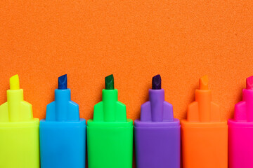 Set of highlighters on orange background, flat lay