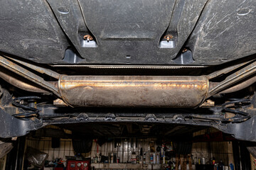 The exhaust system in the car seen from below, visible end silencer, the car is on the lift in the car workshop.