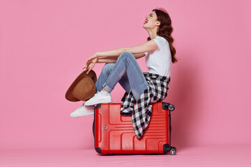 cheerful woman with red suitcase travel pink background flight