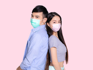 Young couple standing back to back with mask