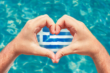 Summer vacation in Greece concept. Male hands making heart shape with Greece flag inside. Beautiful...
