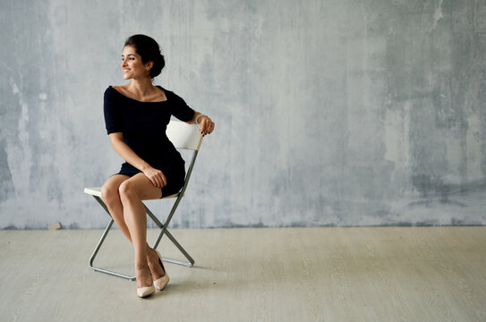 woman sitting on a chair in a black dress posing fashion luxury