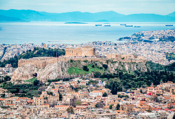 Fototapeta na wymiar View of the Acropolis of Athens seen from Lycabettus Hill. The Filopappos Hill and the Saronic gulf, with the port and the city of Piraeus are in the background.
