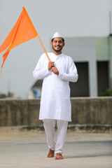 Young indian man (pilgrim) in traditional wear and waving religious flag.