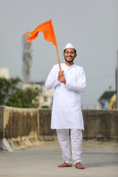 Young indian man (pilgrim) in traditional wear and waving religious flag.