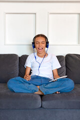 Teenage girl. sitting on the couch listens to aggressive modern music and sings along.