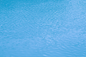 Blue water background. The calm surface of the sea. Ocean. Natural abstract background. Film grain and noise.