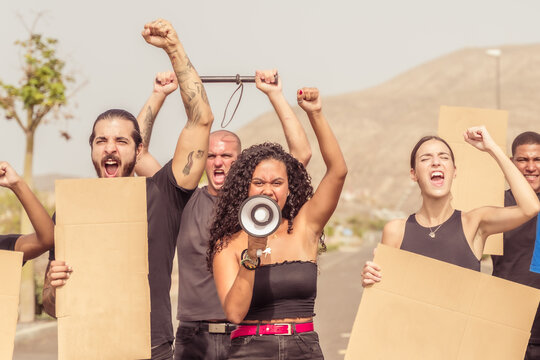 Young People Demonstrate Against The Mandatory Vaccination. Arms Raised In Protest. Group Of Protestors Fists Raised Up In The Air. Racism, Coronavirus, Anti Vax, Equality And Gay Pride Concept. 