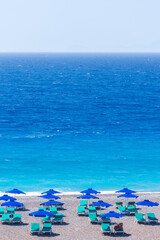 Colorful umbrellas and sunbeds on an empty beach resort - vacation concept on Greece islands in Aegean and Mediterranean seas