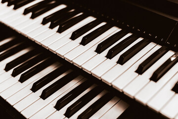 Close focus on upper row of piano with warm tone of black and white.