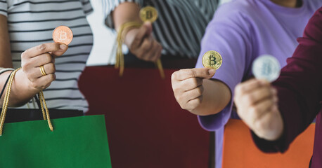 Group of unrecognizable women holding crypto money coins and a variety of colors of shopping bags on hand. Concept of cryptocurrency payment and digital money using in real life of modern people