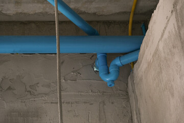 blue plastic water tube install on concrete white wall for building restroom in house site. fixing pipe for maintenance.