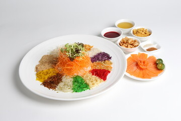 chinese new year colourful lo hei yu sheng with smoked salmon, vegetables and sauces in white gold background asian halal menu for cny festival