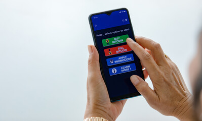 Hand holding smartphones and use finger touch on screen and selecting on buttons of buy and sell application for bitcoin or cryptocurrency digital money trading with copy space