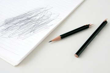 折られた鉛筆とぐちゃぐちゃ書きをされたノート