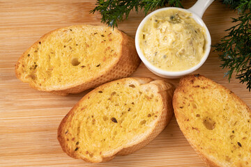 A few slice of garlic bread with a small bowl of garlic butter spread. Selective focus points. Blurred background