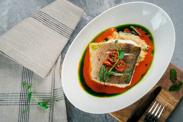 Fried fish fillet of halibut on a plate with tomato sauce. Cod or white fish with sauce and herbs,...