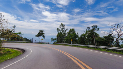 Fototapeta premium Cars driving on zigzag curve road or street on mountain hill with green natural forest trees in rural area of Phetchabun, Thailand. Transportation.