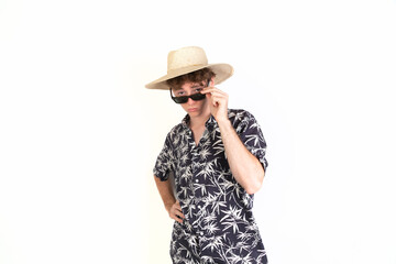 Teenager ready to go to the beach with a hat, sunglasses and a palm trees shirt. portrait, white background, 18-20 years old. White european guy.