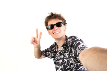 Selfie photo of a teenager raising two fingers doing letter V, victory symbol. Wearing sunglasses and a palm trees shirt. white background, 18-20 years old. White european guy.