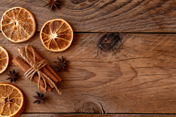 Cinnamon sticks, slices of dried orange, star anise on wooden background with copy space. Top view. Christmas and New Year celebration concept.