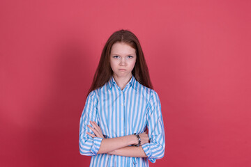 Fototapeta premium Little kid girl 13 years old in blue dress isolated on pink background look to camera with angry gaze crossed arms