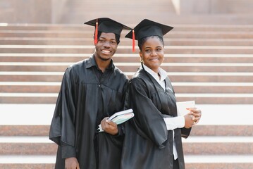 education, graduation and people concept - group of happy international students in mortar boards and bachelor gowns with diplomas