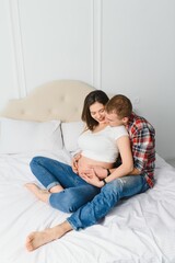 Young pregnant woman with husband on sofa in room