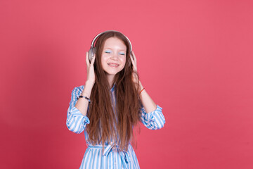 Little kid girl 13 years old in blue dress with brackets isolated on pink background in wireless headphones happy smiling