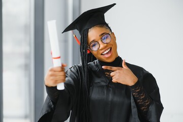happy african american female student with diploma at graduation