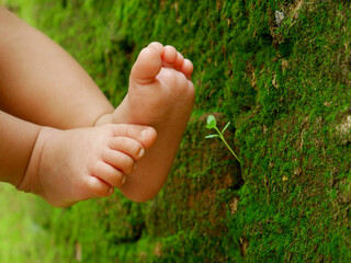 New born baby kid feet presented on green blur wall background, kids lifestyle concept image