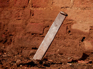 Iron giant nails inserted on soil field at brick wall background for industrial presentation.