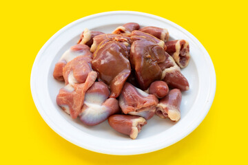 Mixed chicken entrails in white plate on yellow background.