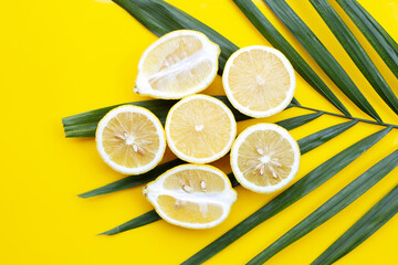 Fresh lemon on tropical palm leaves on yellow background.