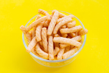 Prawn cracker sticks in glass bowl on yellow background. Shrimp crispy rice snack