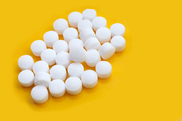 Naphthalene mothballs on yellow backgrond.