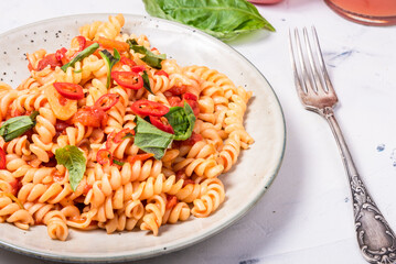 Serving of veggie marinara pasta in a plate with hot chili and basil, close-up