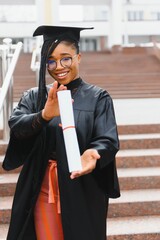 happy african american female student with diploma at graduation