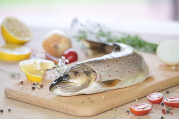 Raw trout on the table with a slice of lemon, salt and spices.
