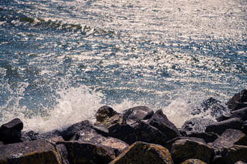 Meeresgischt bricht in Wellen an Felsen am Strand
