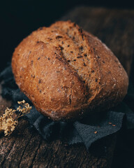 Freshly baked wholemeal rye bread with many seeds in its composition placed on a wooden surface.