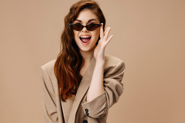 happy women in brown glasses and in a coat on a beige background