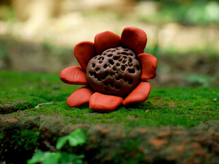 hand crafted clay art sunflower lying on natural green grass surface at blur wide range background.