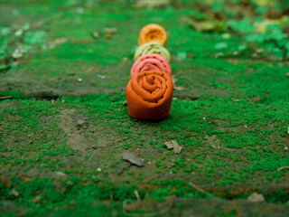 Beautiful rose flower clay made art object presented on sequence on green surface at natural field.