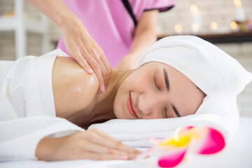 Young woman relaxing in spa salon. Young beautiful white woman lying on a massage table and is being massaged.