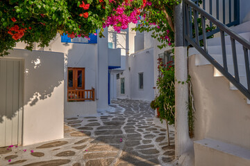 Beautiful traditional street in Greek island town. Whitewashed houses, bougainvillea in blossom, cobblestone. Mykonos, Greece