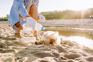 Woman collect plastic garbage on sandy beach of the sea. Spilled garbage on the beach. Environmental pollution concept